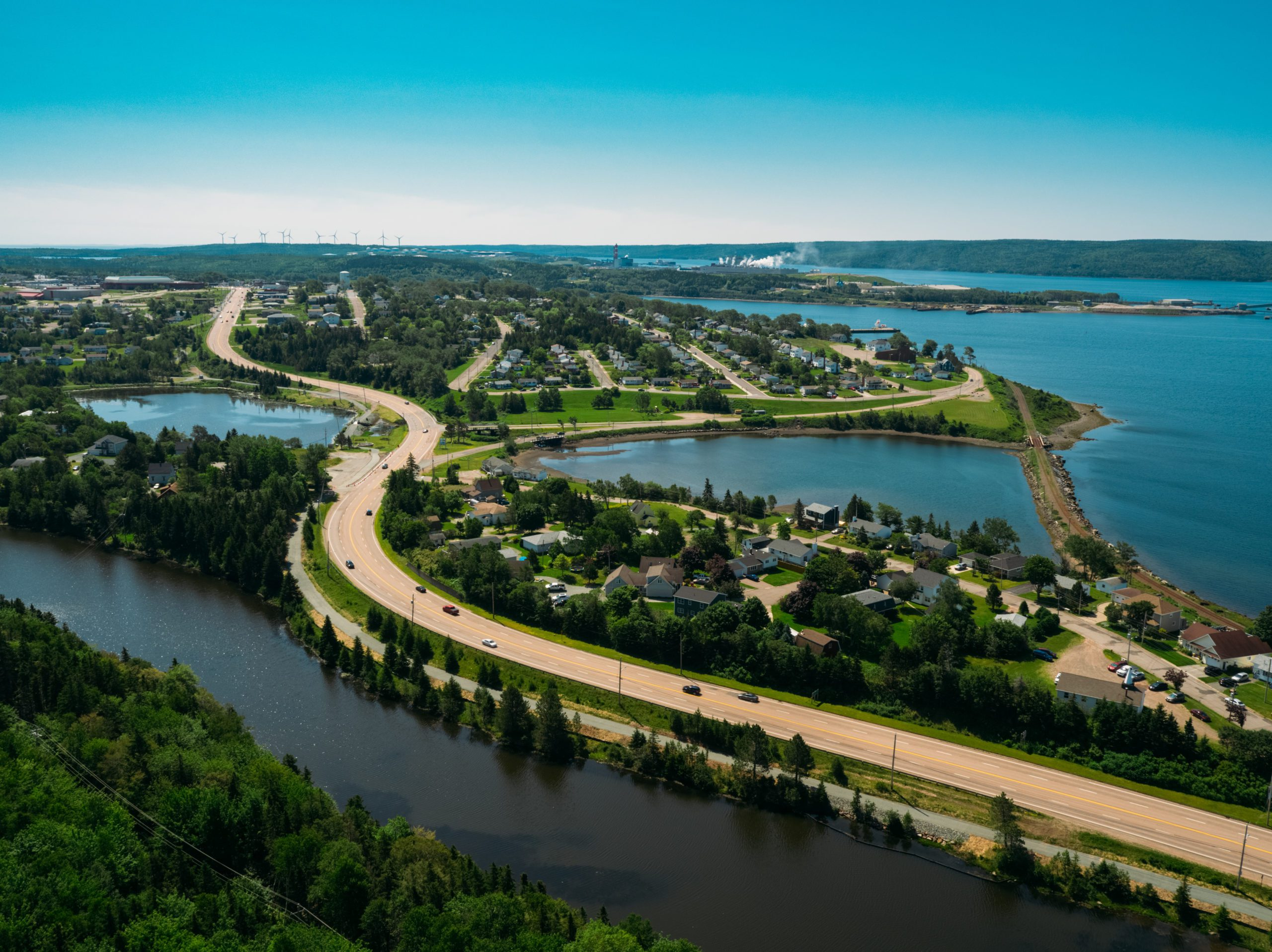 An aerial view of homes, trees, roads, and shoreline around Port Hawkesbury